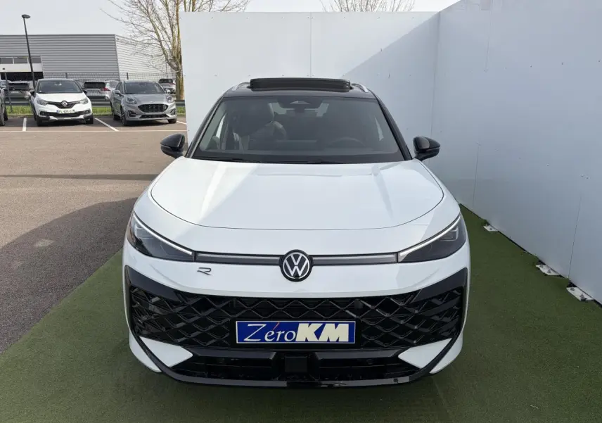 Vue avant d'un Volkswagen T-Roc blanc pur avec toit noir et calandre R-Line noire, sur fond extérieur neutre.