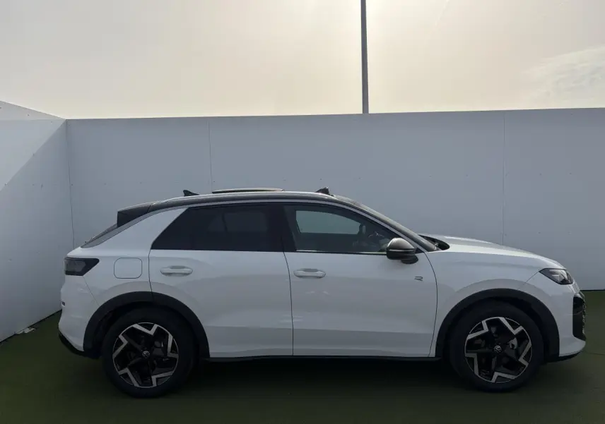 Profil droit du Volkswagen T-Roc blanc pur avec toit noir et jantes 18 pouces Coventry en extérieur.