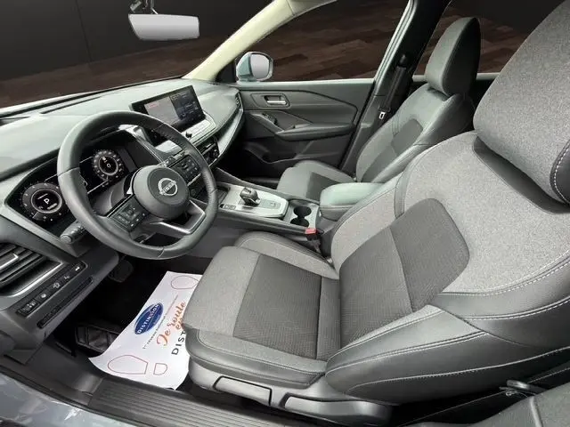 Vue intérieure côté conducteur du Nissan Qashqai gris foncé 2025, avec tableau de bord digital et sièges tissu gris.