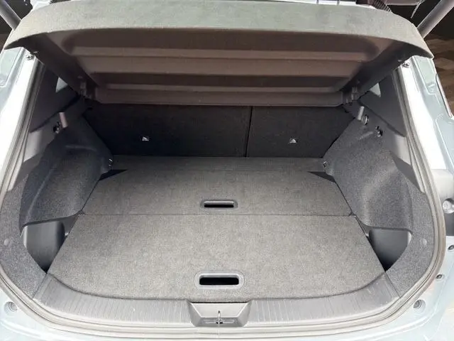 Coffre ouvert vu de l'arrière d'un Nissan Qashqai gris foncé, avec banquette arrière rabattue et espace de chargement plat.