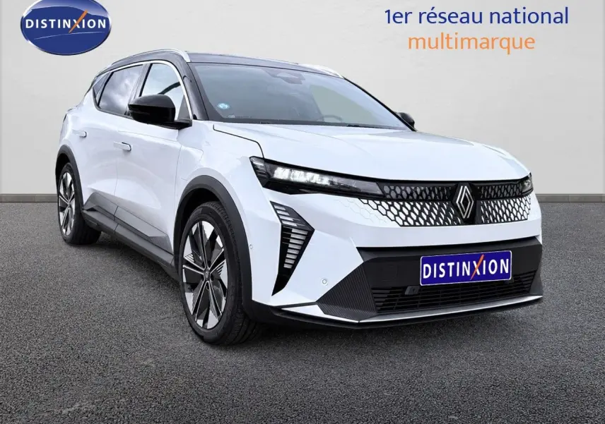 Renault Scénic 5 électrique blanc en 3/4 avant droit, avec calandre à motif nid d'abeille et jantes stylisées.