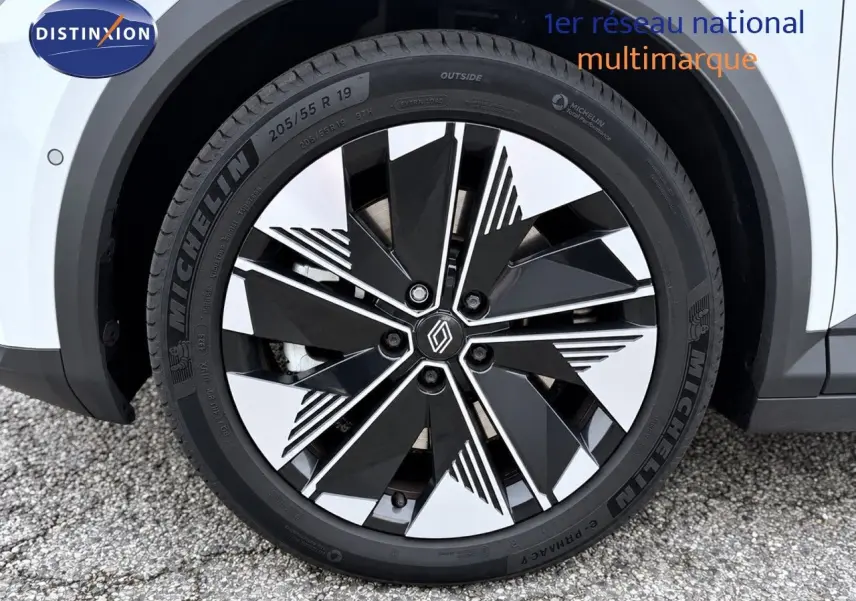 Gros plan sur la roue avant droite du Renault Scenic 5 blanc 2024, mettant en valeur la jante noire et argentée au design moderne.