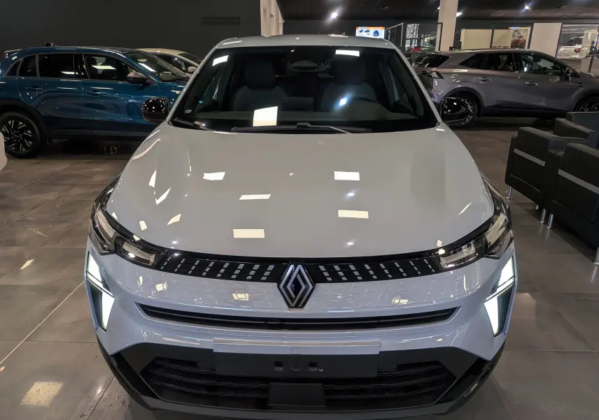 Vue frontale du Renault Captur 2025 gris rafale avec feux LED allumés dans un showroom.