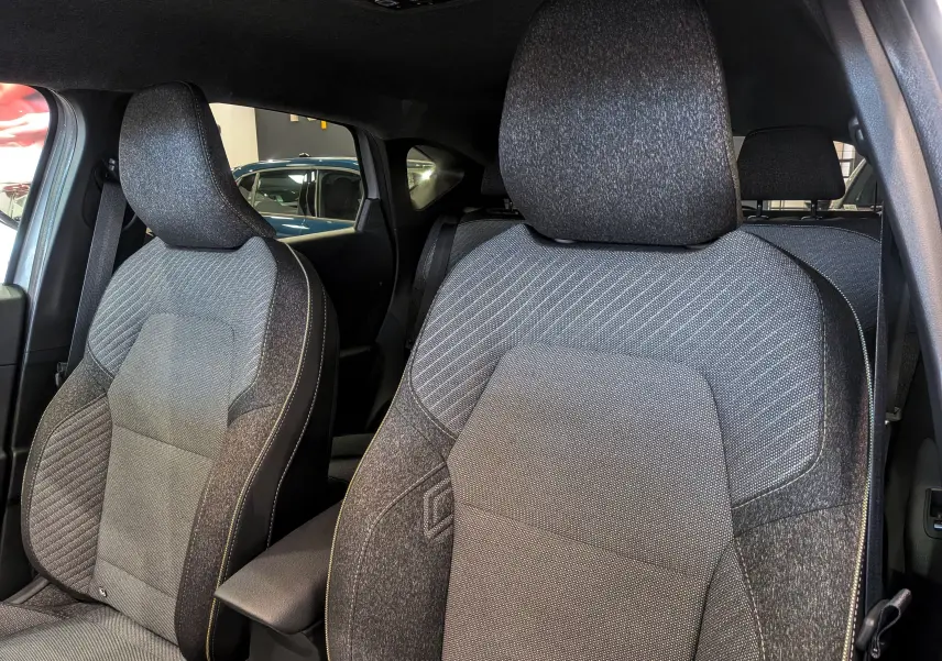 Gros plan sur les sièges avant en tissu gris du Renault Captur Mild Hybrid 160 CH EDC TECHNO 2025, intérieur moderne.