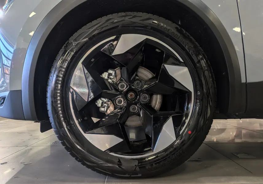 Gros plan sur la roue avant droite du Renault Captur gris rafale, mettant en valeur la jante biton noire et argentée au design géométrique.