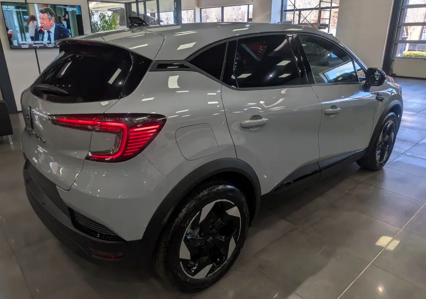 Vue 3/4 arrière droite du Renault Captur gris rafale avec jantes noires biton et vitres teintées en showroom.