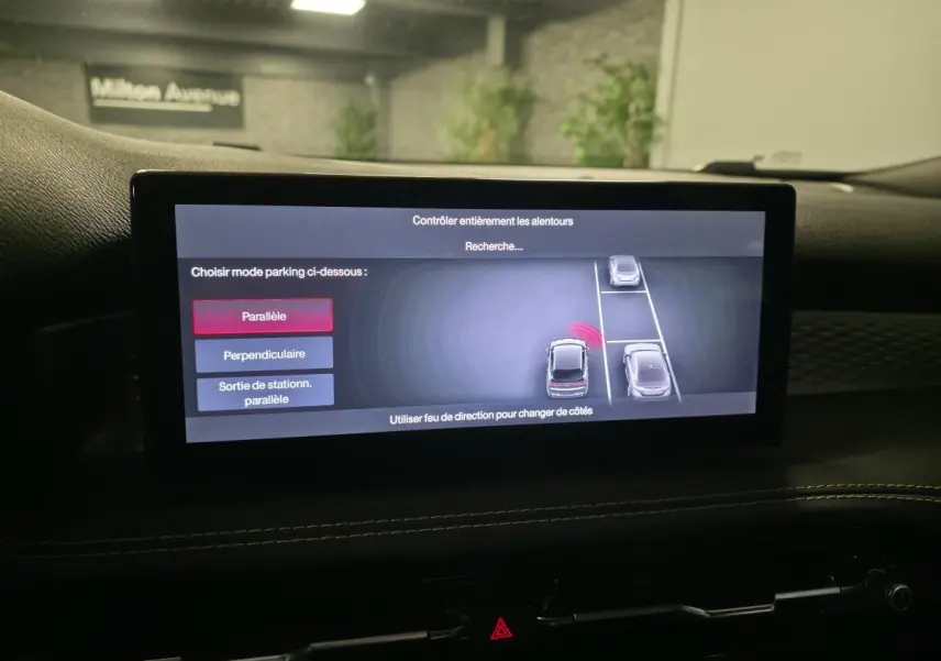 Écran tactile intérieur affichant l'aide au stationnement 360° du SUV Alfa Romeo Tonale rouge, vue de face cabine.