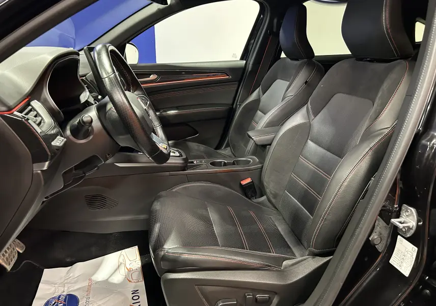 Vue intérieure côté conducteur du Renault Arkana noir, sièges et volant en cuir avec surpiqûres rouges, finition RS Line.