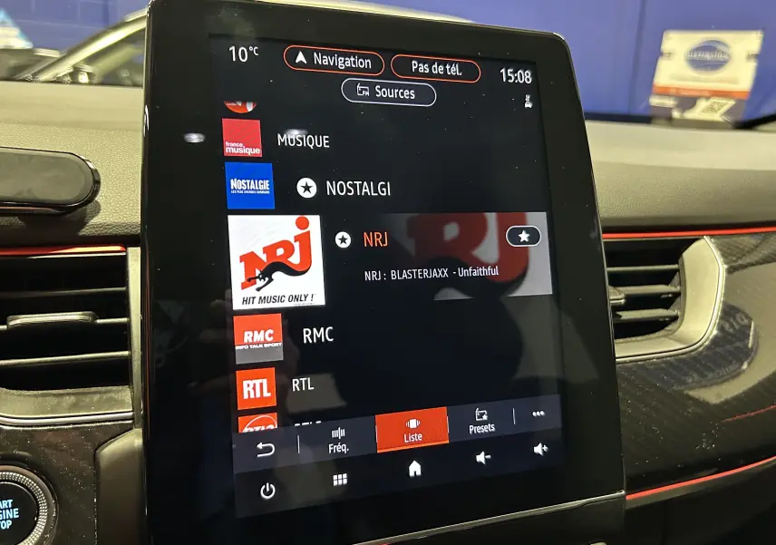 Vue rapprochée de l’écran tactile central du Renault Arkana E-Tech noir, affichant les stations radio avec interface moderne.
