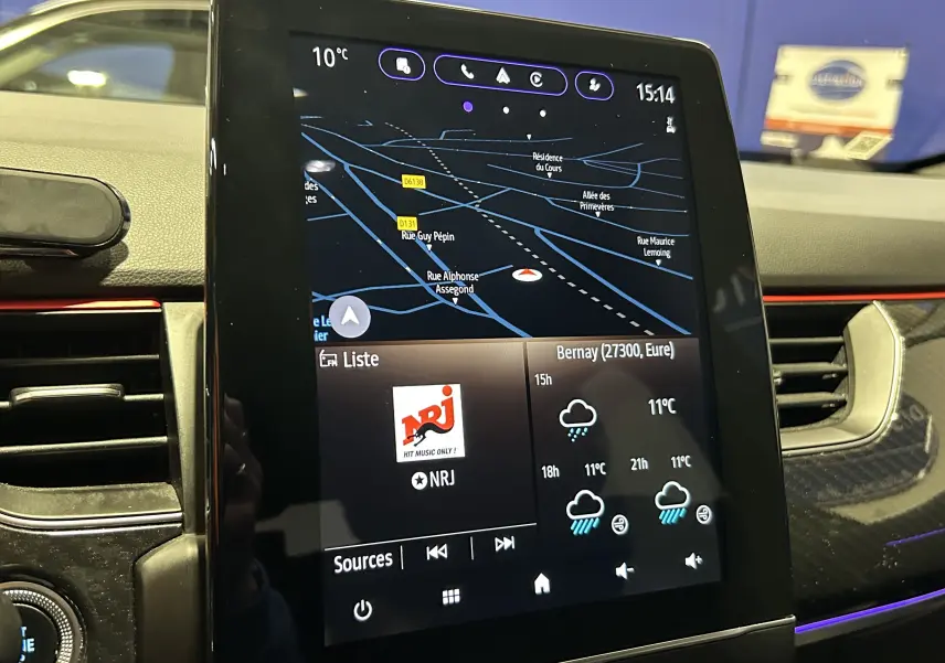 Écran tactile central du tableau de bord Renault Arkana noir, affichant navigation, météo et radio NRJ.
