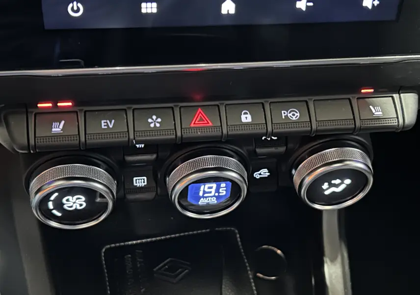 Gros plan sur la console centrale de la Renault Arkana noire, avec commandes de climatisation et sièges chauffants activés.