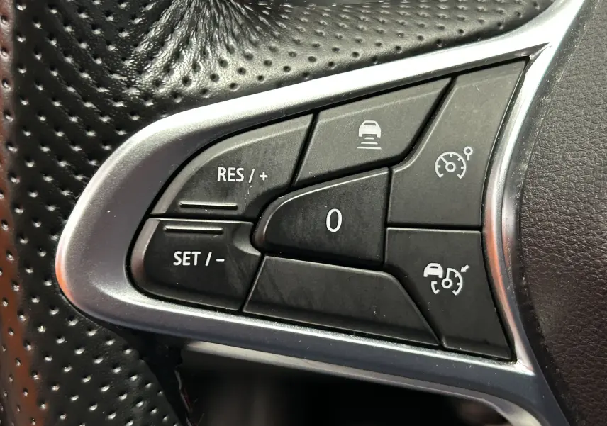 Gros plan sur les commandes de régulateur de vitesse au volant en cuir perforé noir du Renault Arkana E-Tech 2022.