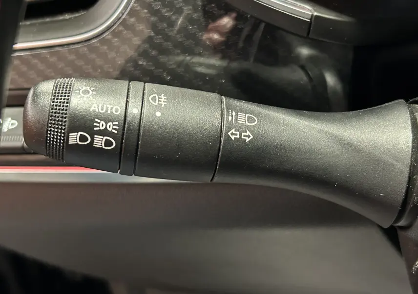 Gros plan sur la commande des feux et clignotants à gauche du volant dans l’habitacle d’un Renault Arkana noir.