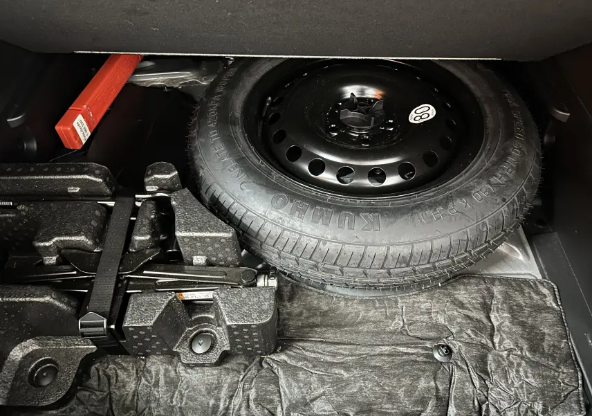 Vue du coffre montrant la roue de secours et les outils de bord du Renault Arkana noir E-Tech 145ch RS Line 2022.