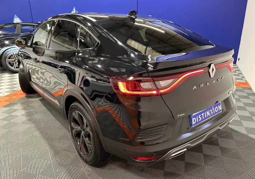 Vue 3/4 arrière droite d’un Renault Arkana noir avec feux LED allumés dans un showroom.