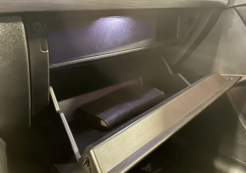Gros plan sur la boîte à gants ouverte de la CUPRA Formentor noire, avec un étui noir à l'intérieur, éclairage intérieur visible.