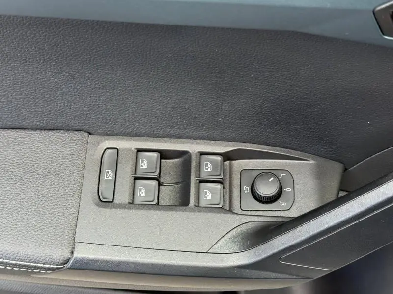 Gros plan sur les commandes de lève-vitres et réglage des rétroviseurs côté conducteur du SEAT Arona gris Magnétique Métal 2025.