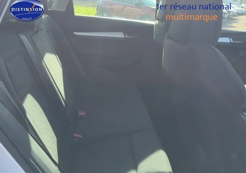 Vue intérieure côté gauche des sièges arrière gris du Skoda Karoq 1.5 TSI 2025 avec accoudoir central.