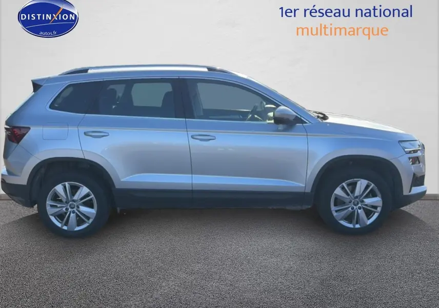 Profil droit d'un Skoda Karoq gris 2025 avec barres de toit et jantes alliage visibles.