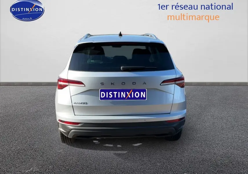 Vue arrière d'un Skoda Karoq gris 2025 avec feux LED et barres de toit visibles sur fond neutre.