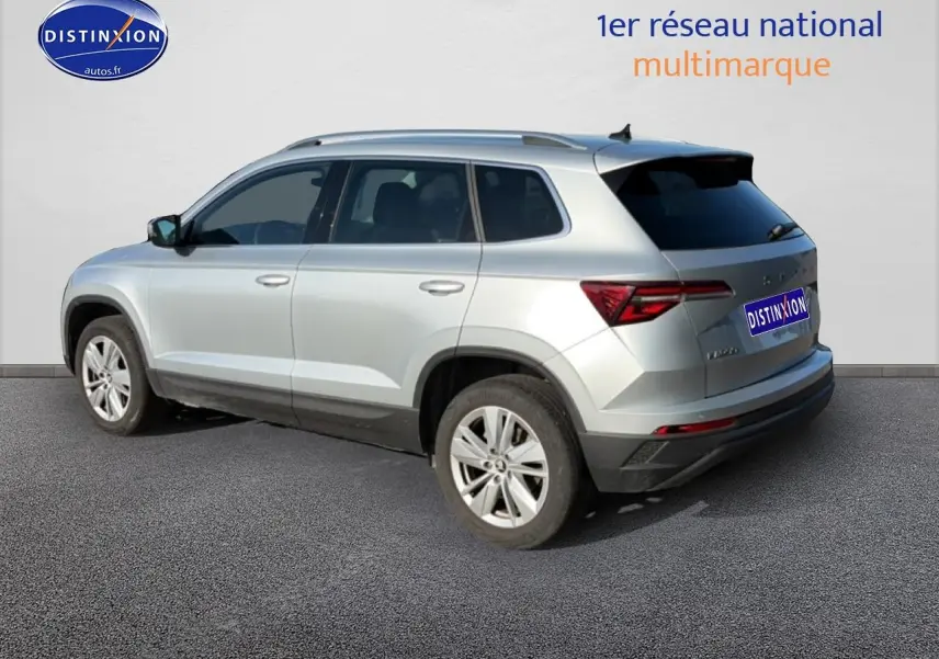 Vue 3/4 arrière droite d'un Skoda Karoq gris avec jantes alu et vitres arrière surteintées.