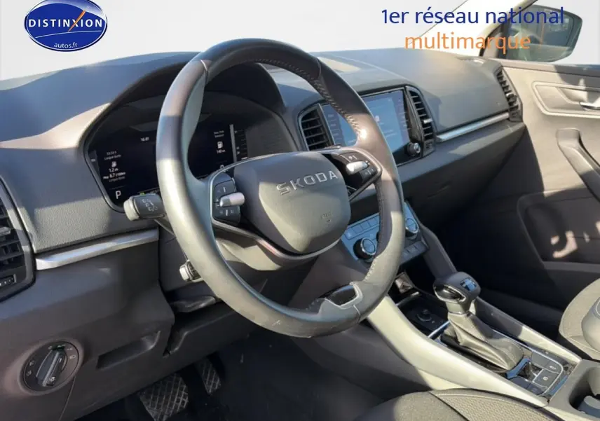 Vue intérieure côté conducteur du Skoda Karoq gris 2025, mettant en valeur le volant multifonction et la console centrale.