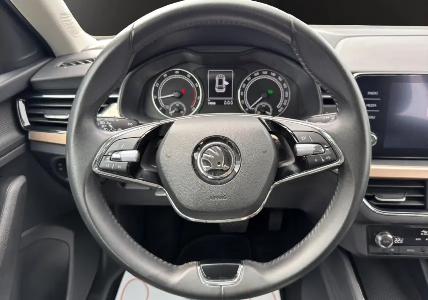 Vue rapprochée du volant cuir multifonctions et du tableau de bord digital du Skoda Kamiq 2023 gris clair.