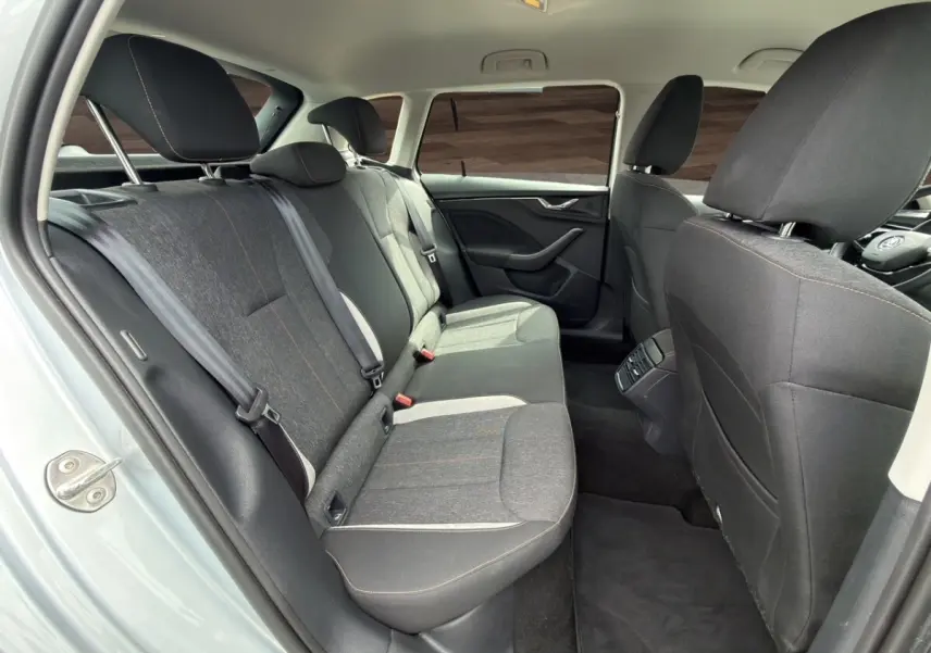 Vue intérieure côté gauche des sièges arrière gris foncé du Skoda Kamiq 2023 avec détails couture orange et accoudoir central.