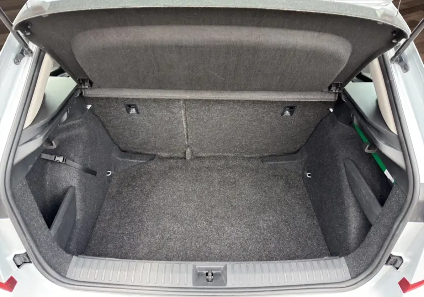 Coffre ouvert vu de l'arrière d'un Skoda Kamiq gris clair 2023 avec intérieur de coffre en tissu gris.
