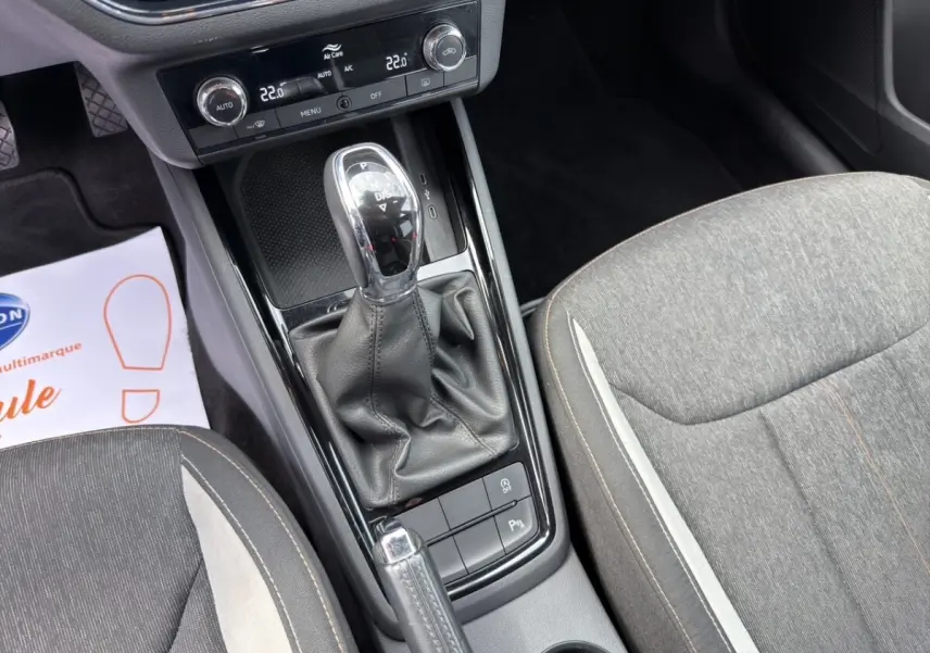 Vue rapprochée de la console centrale et levier de vitesse automatique d’un Skoda Kamiq gris clair, sièges tissu gris.