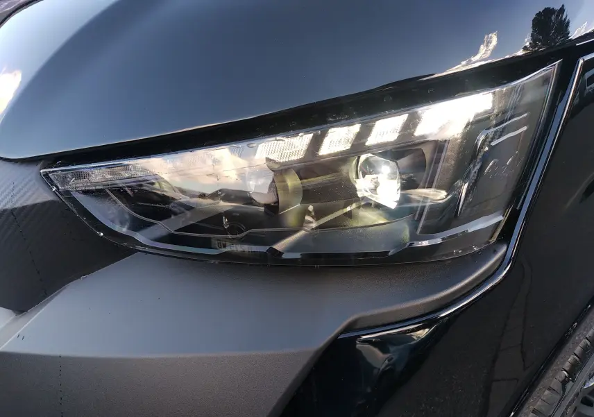 Gros plan sur le phare avant droit LED du Ligier JS60 Nouvelle Revo D+ Select noir intense, avec détails de la carrosserie brillante.