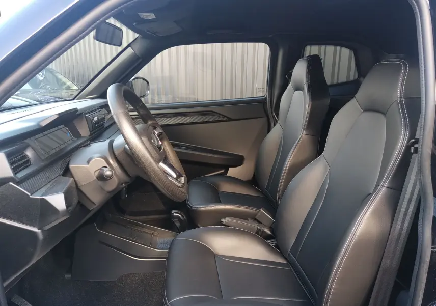 Vue intérieure côté conducteur de la LIGIER JS60 Nouvelle Revo D+ Select, sièges noirs avec surpiqûres blanches et finition carbone.