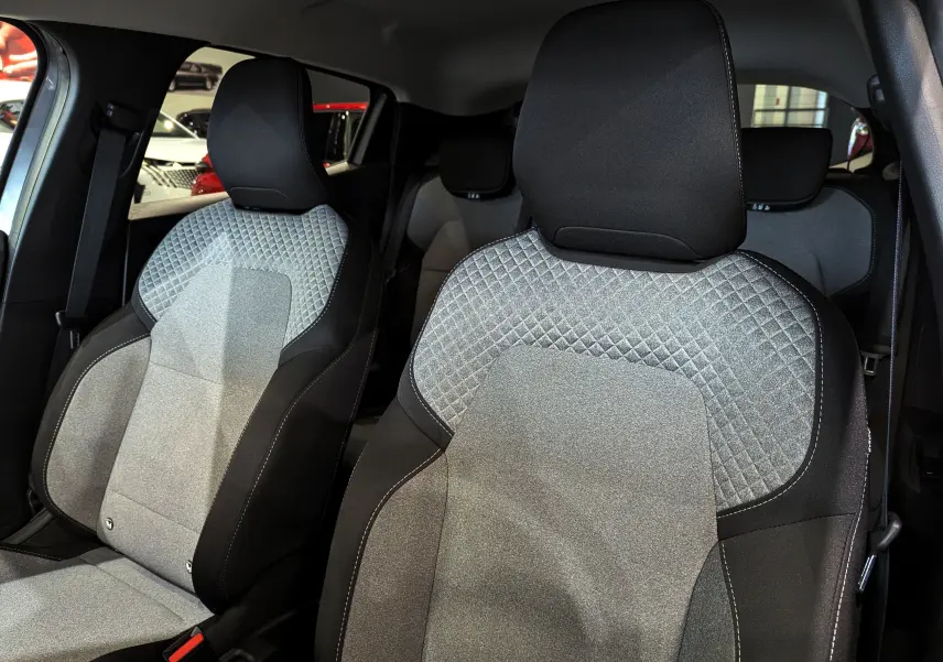 Gros plan sur les sièges avant en tissu gris clair et noir de la Renault Clio V Blue dCi 100 CH Evolution 2025.