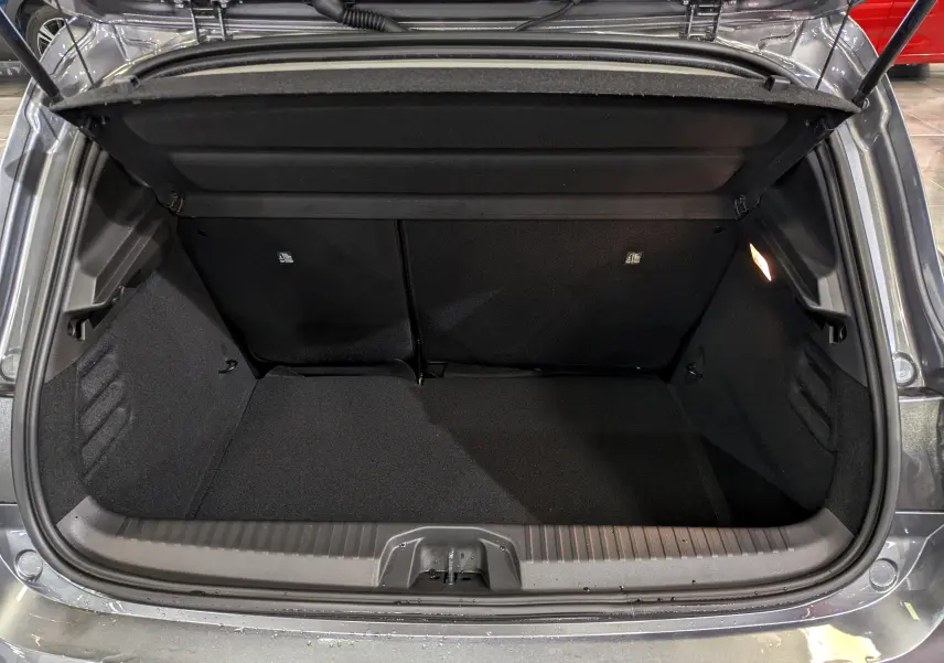 Coffre ouvert vu de l'arrière d'une Renault Clio V Blue dCi 100 CH Evolution gris schiste, intérieur noir et éclairage latéral.