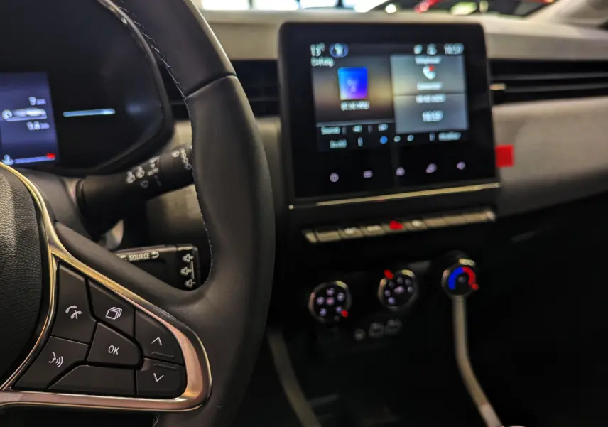 Intérieur de Renault Clio V Blue dCi 100 CH Evolution 2025, vue sur volant et écran tactile central avec commandes climatiques.