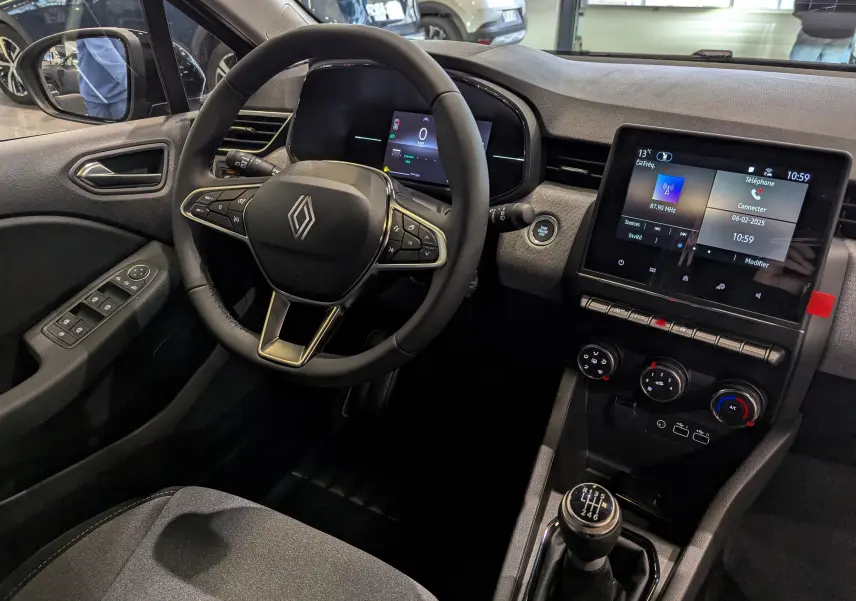 Vue intérieure côté conducteur de la Renault Clio V Blue dCi 100 Gris Schiste avec volant multifonction et écran tactile central.