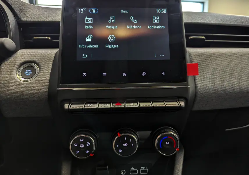 Vue rapprochée du tableau de bord de la Renault Clio V avec écran tactile et commandes de climatisation en tissu gris.