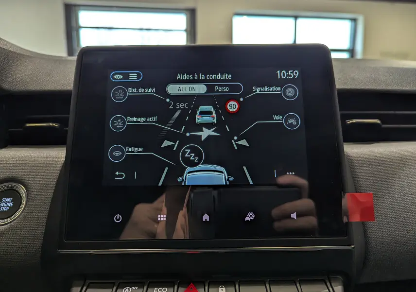 Écran tactile central de la Renault Clio V gris schiste montrant les aides à la conduite avec options activées.
