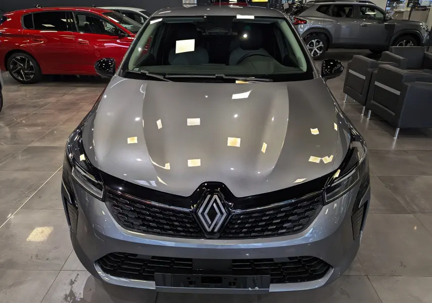 Vue avant rapprochée d'une Renault Clio V Blue dCi 100 Evolution gris schiste dans un showroom lumineux.