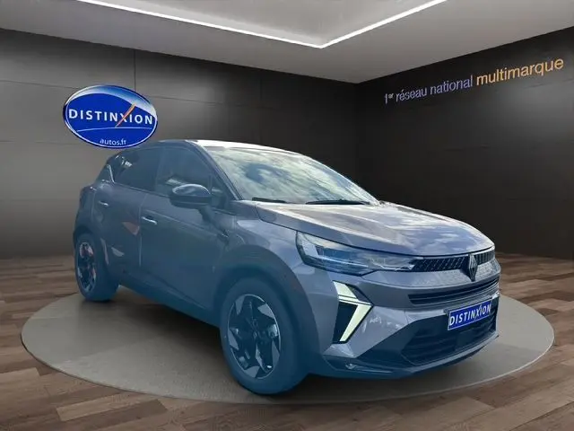 Renault Captur 2025 gris Cassiopée et toit noir, vue 3/4 avant mettant en valeur la calandre et les phares LED distinctifs.