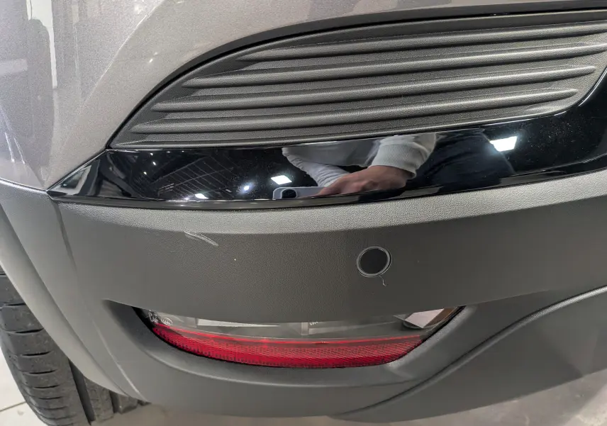 Gros plan sur le feu arrière droit et le pare-chocs gris cassiopé du Renault Captur 2025 avec insert noir brillant.