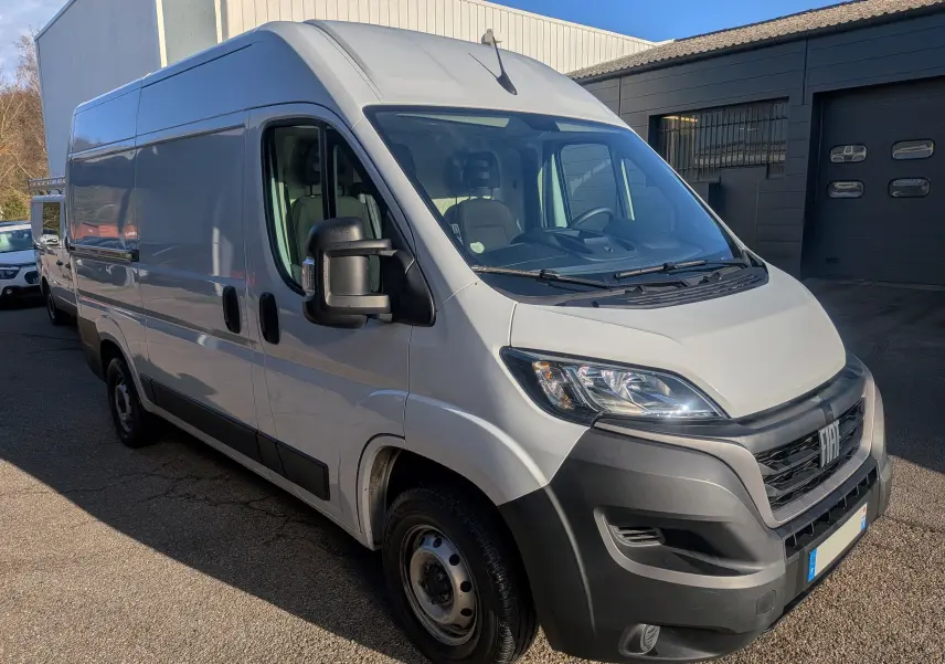 Vue 3/4 avant droite d’un FIAT Ducato Fourgon blanc 2022 avec pare-chocs noirs et rétroviseurs élargis.