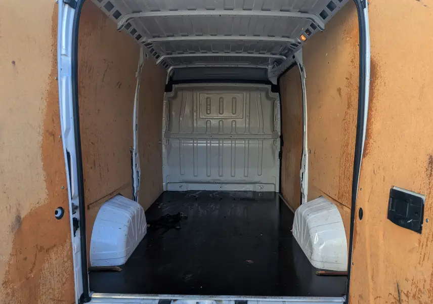 Vue intérieure arrière du fourgon blanc Fiat Ducato 2022, montrant l’espace de chargement avec parois en bois et sol noir.