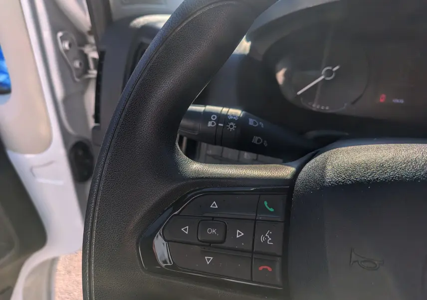 Gros plan sur le volant noir du Fiat Ducato Fourgon blanc 2022, montrant les commandes multifonctions côté gauche.
