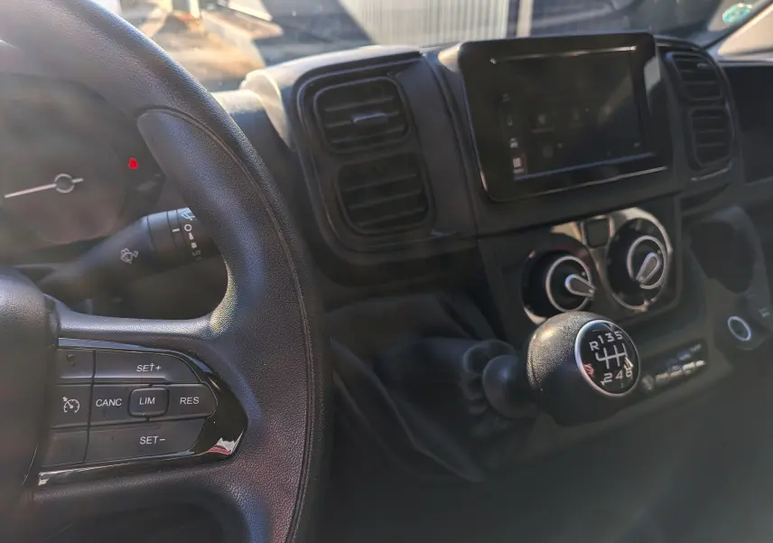 Vue intérieure du tableau de bord du Fiat Ducato Fourgon 2022, avec volant noir et levier de vitesse manuel en gros plan.