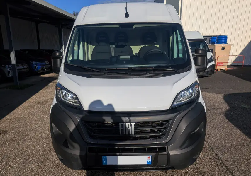 Vue de face d’un FIAT Ducato Fourgon blanc 2022 avec calandre noire et pare-chocs avant robuste en plastique noir.