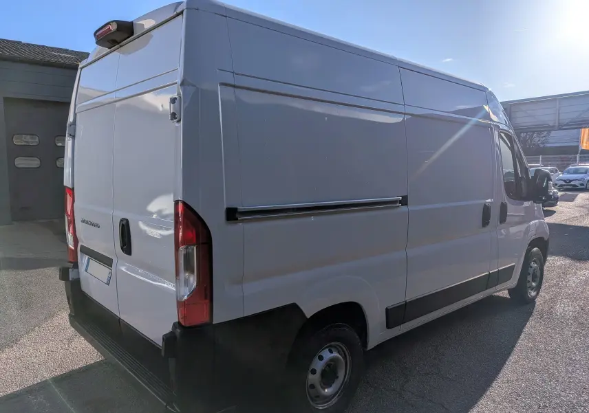 Fourgon blanc Fiat Ducato 3.0 M H2 vu en 3/4 arrière droit, avec porte latérale coulissante et feux arrière rouges.