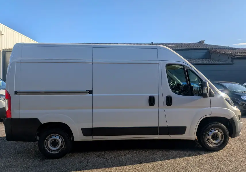Vue de profil côté droit d’un fourgon FIAT Ducato blanc 2022 avec porte coulissante et jantes acier noires.