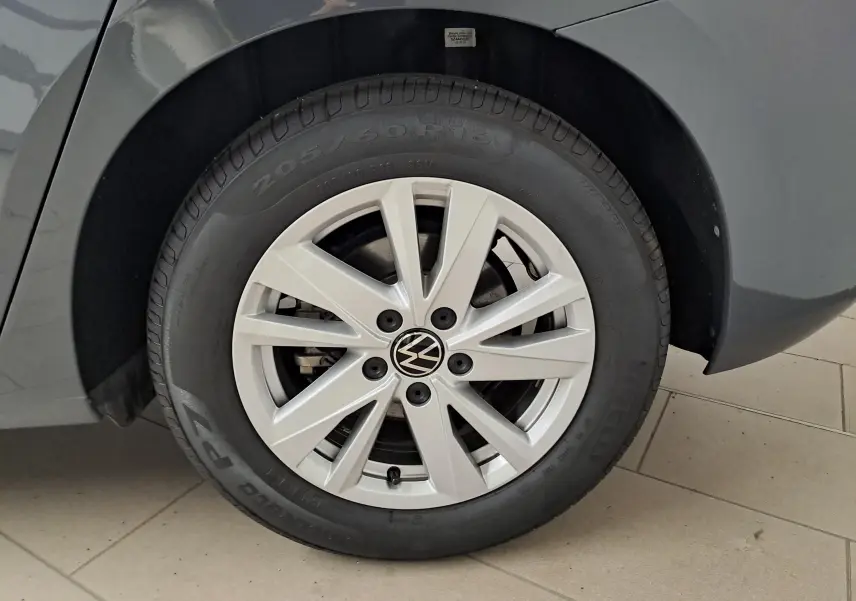 Gros plan sur la roue avant gauche du Volkswagen Touran gris Dauphin 2024 avec jante alliage et logo VW central.