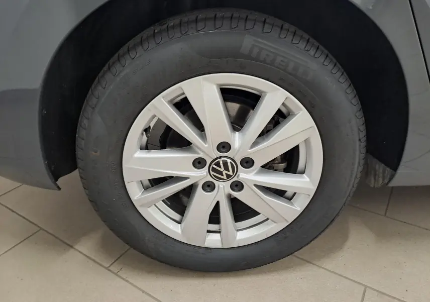 Gros plan sur la roue avant gauche du Volkswagen Touran gris Dauphin, mettant en valeur la jante alliage et le logo VW central.